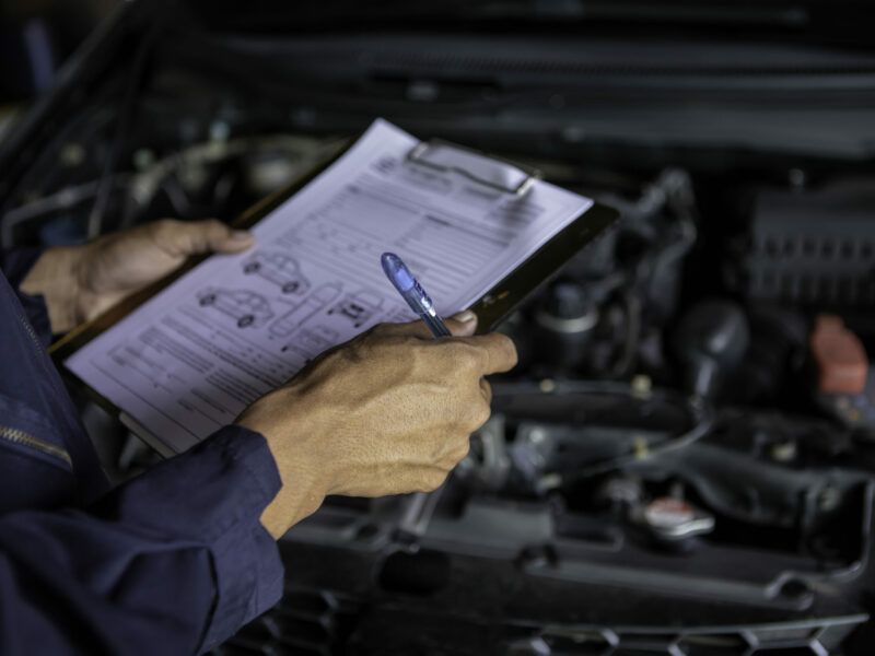 A mechanic service car in garage is check a list cars.